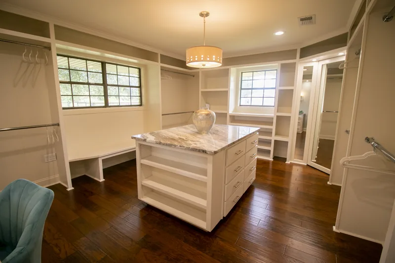 Walk-in closet with center storage island and dark wood flooring