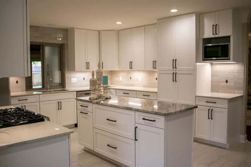 Remodeled white kitchen with granite island and cabinetry