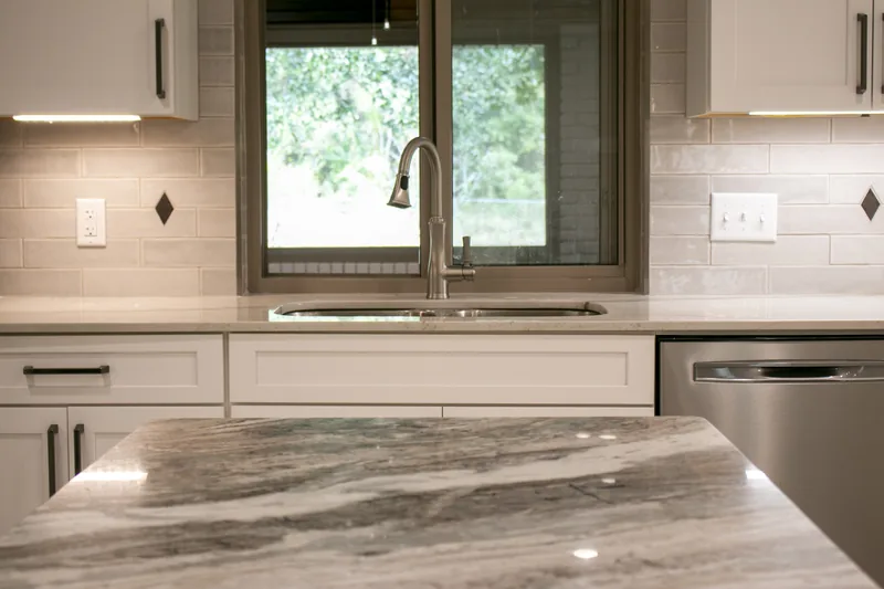 Kitchen sink and granite counter beneath a window
