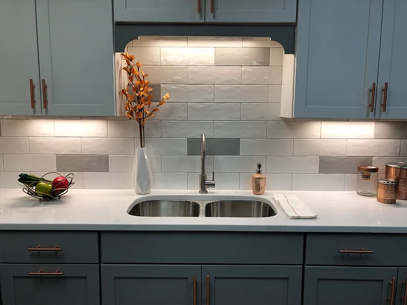 Blue-gray kitchen cabinetry with a light countertop and tile backsplash
